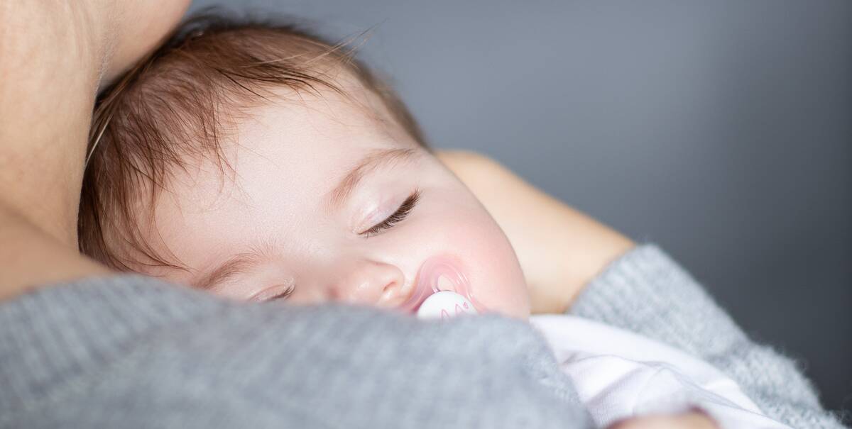 Baby schläft auf dem Arm seiner Mutter.